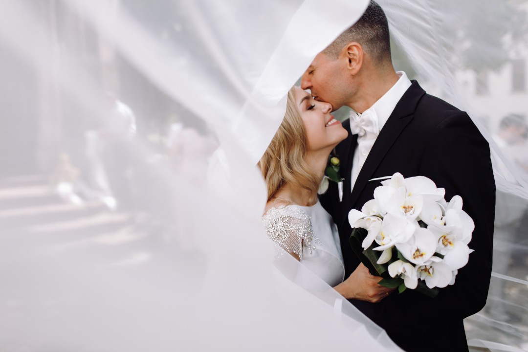 26433groom-black-tuxedo-hugs-tender-stunning-bride-while-they-stand.jpg